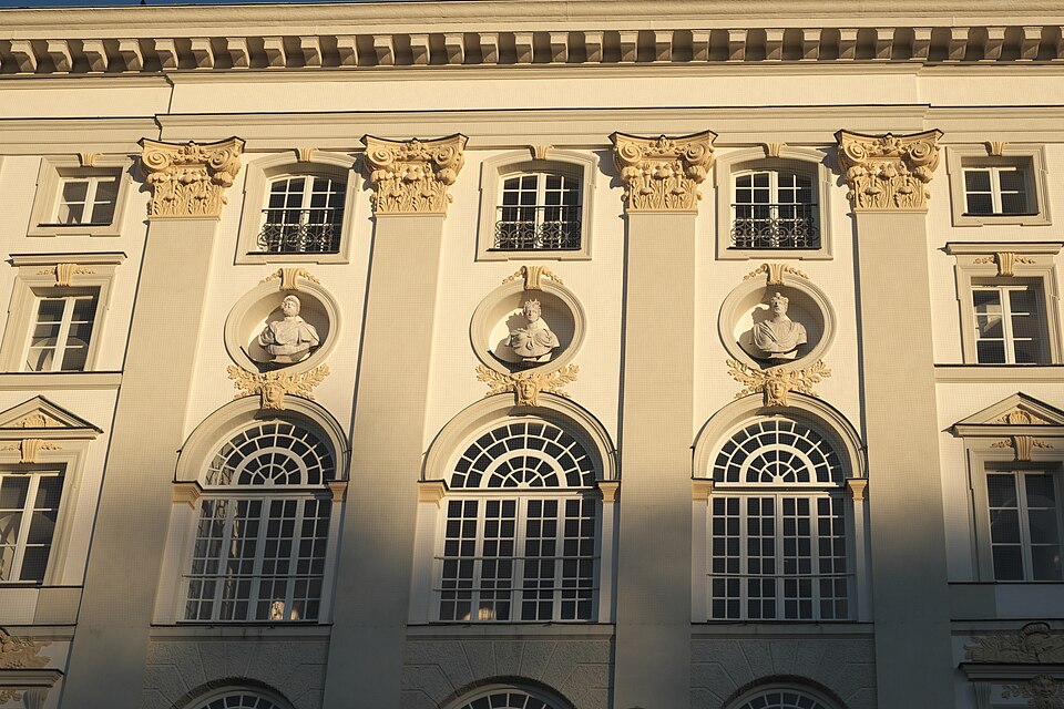 The wide Baroque facade of Schloss Nymphenburg reflected in its canal.